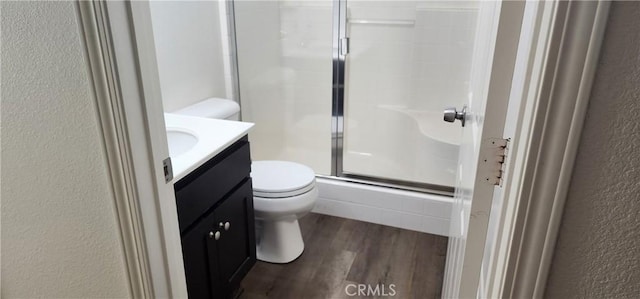 bathroom featuring vanity, hardwood / wood-style flooring, a shower with door, and toilet