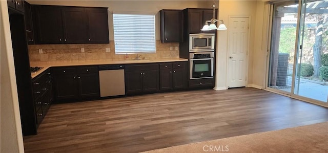 kitchen with pendant lighting, sink, appliances with stainless steel finishes, backsplash, and light wood-type flooring