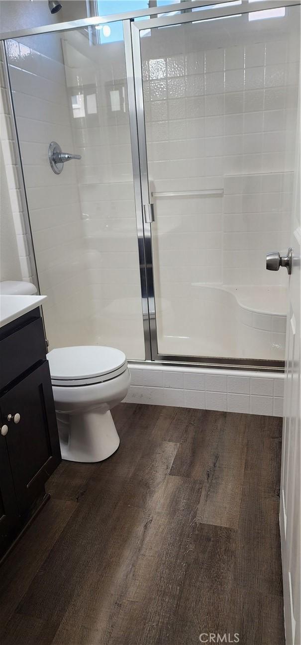 bathroom featuring an enclosed shower, hardwood / wood-style floors, vanity, and toilet