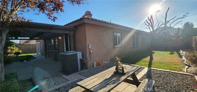 view of side of property with cooling unit, a patio, and a lawn