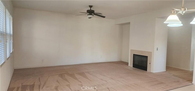 unfurnished living room with ceiling fan, light colored carpet, and a tiled fireplace