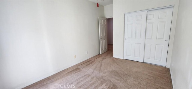 unfurnished bedroom with light carpet and a closet