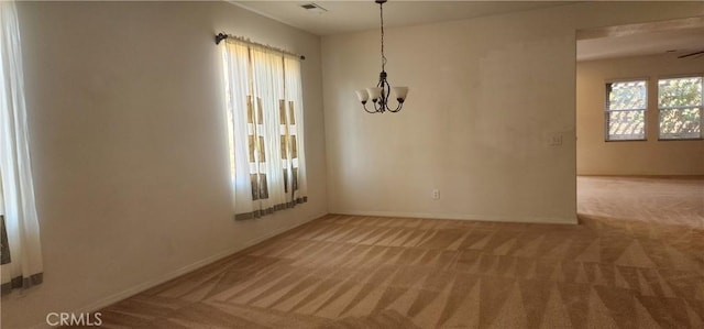 carpeted spare room featuring an inviting chandelier