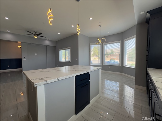 kitchen featuring a center island, light stone countertops, decorative light fixtures, and ceiling fan