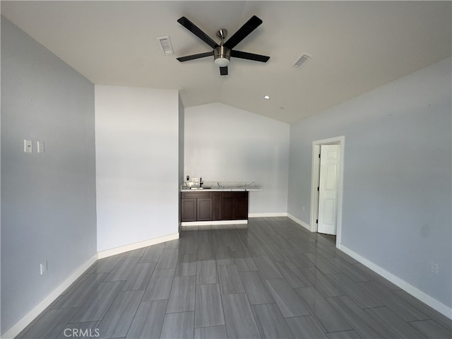 spare room featuring sink, ceiling fan, wood-type flooring, and vaulted ceiling