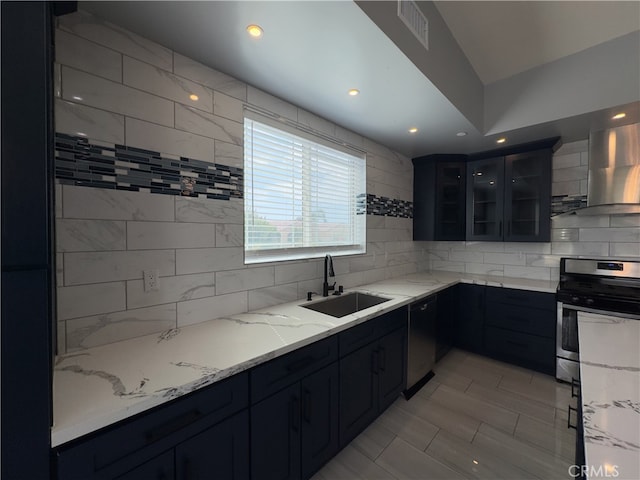 kitchen featuring black dishwasher, light stone counters, stainless steel stove, wall chimney exhaust hood, and sink