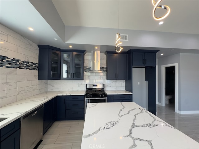 kitchen with wall chimney exhaust hood, light stone countertops, stainless steel appliances, and pendant lighting