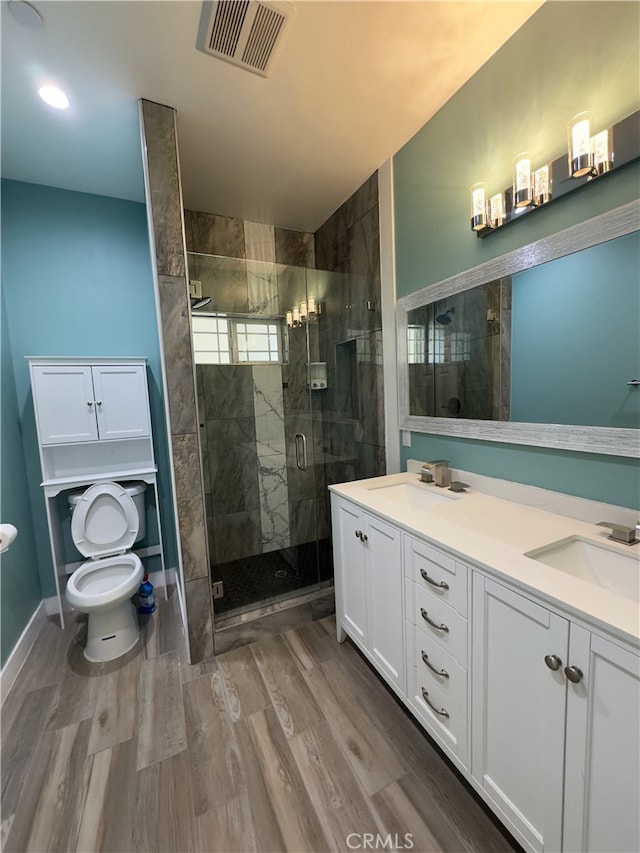 bathroom featuring toilet, an enclosed shower, hardwood / wood-style flooring, and vanity