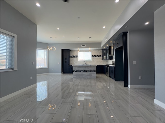 kitchen featuring stainless steel range, decorative light fixtures, a healthy amount of sunlight, and sink