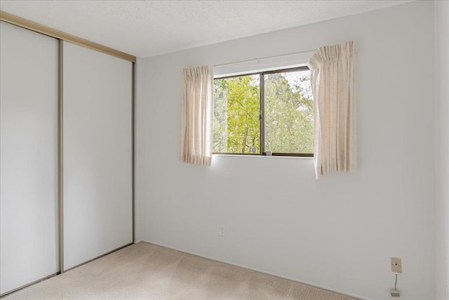 unfurnished bedroom featuring a closet, carpet, and a textured ceiling