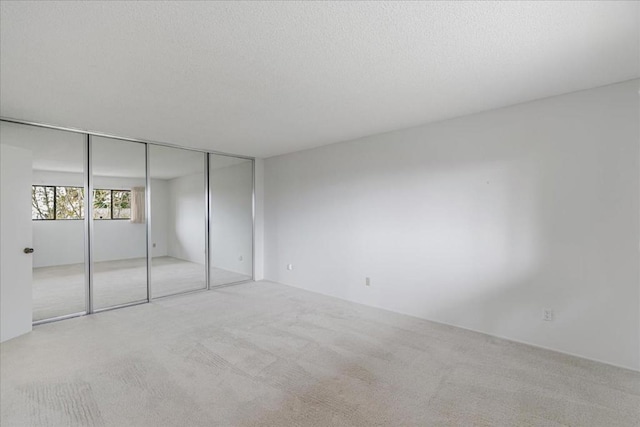 unfurnished bedroom with light carpet, a closet, and a textured ceiling