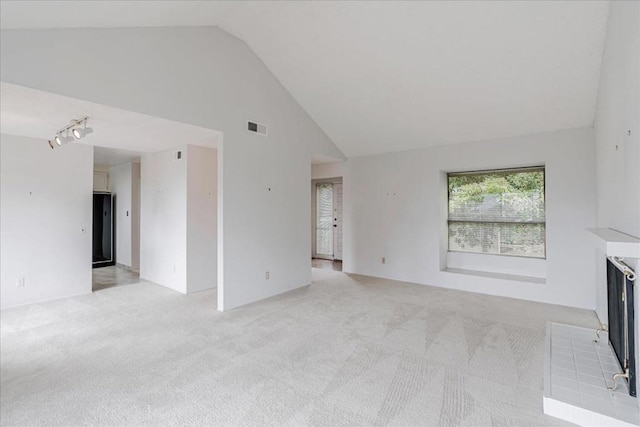 unfurnished living room with high vaulted ceiling and light colored carpet