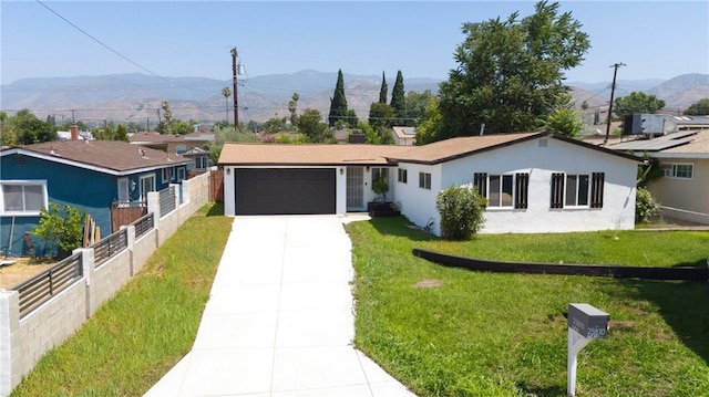 ranch-style home with a mountain view, a front lawn, and a garage