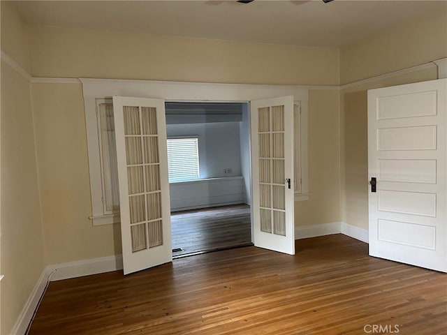 unfurnished room with baseboards, french doors, and wood finished floors