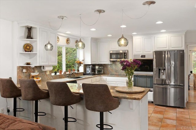 kitchen featuring pendant lighting, sink, appliances with stainless steel finishes, tasteful backsplash, and white cabinetry