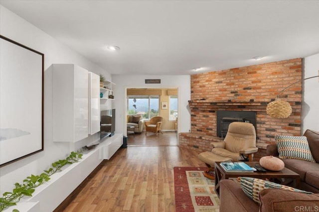 living room featuring a brick fireplace and light wood-type flooring