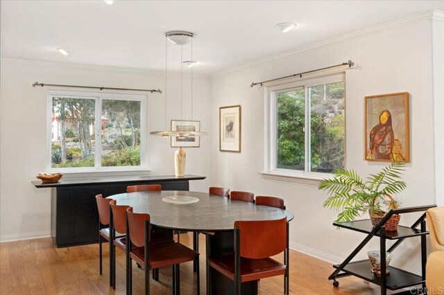 dining space with crown molding and light hardwood / wood-style flooring