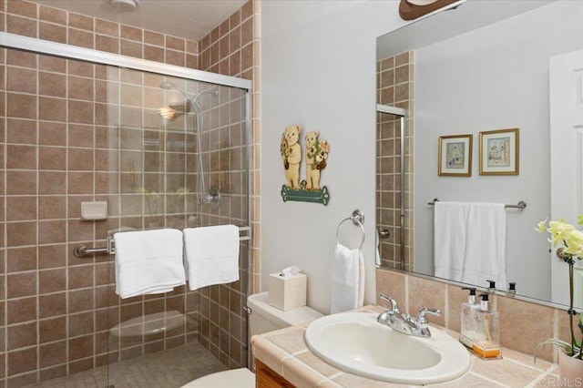 bathroom featuring a shower with door, vanity, and toilet