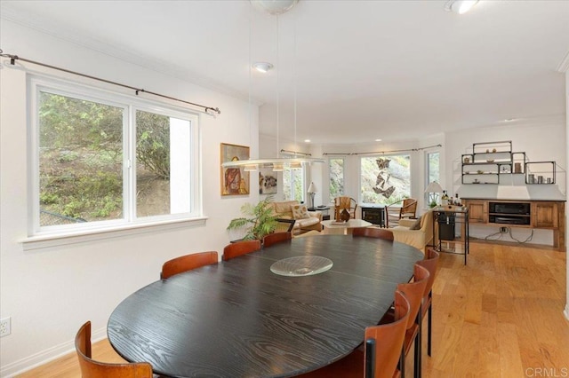 dining room featuring crown molding, plenty of natural light, and light hardwood / wood-style floors