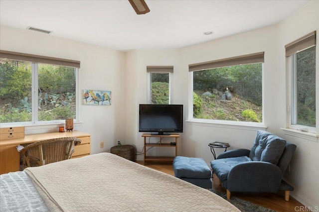 bedroom with hardwood / wood-style floors, ceiling fan, and multiple windows