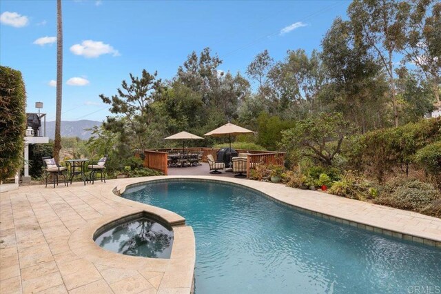 view of pool with a deck with mountain view, an in ground hot tub, and a patio