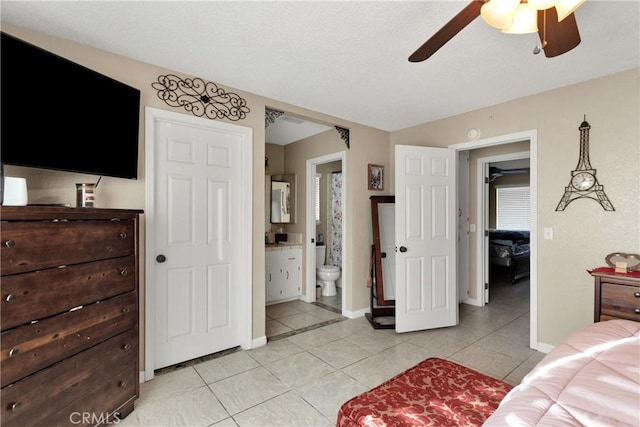 bedroom with ensuite bath, light tile patterned flooring, and ceiling fan