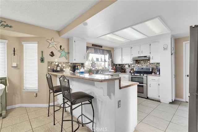 kitchen with white cabinets, double oven range, tasteful backsplash, and kitchen peninsula