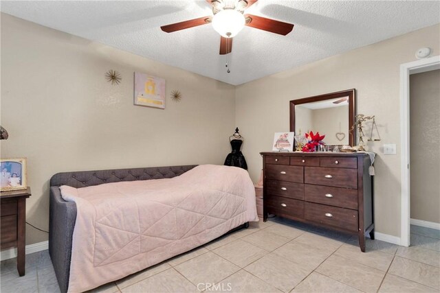 bedroom with ceiling fan, a textured ceiling, and light tile patterned floors