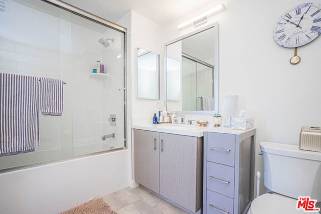 full bathroom featuring combined bath / shower with glass door, vanity, and toilet