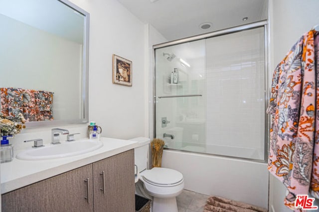 full bathroom with combined bath / shower with glass door, vanity, tile patterned floors, and toilet