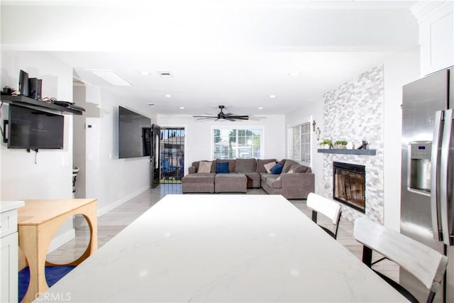 living room featuring ceiling fan, a fireplace, and light hardwood / wood-style flooring