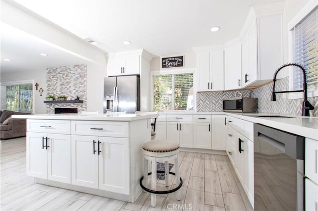 kitchen featuring decorative backsplash, white cabinetry, sink, and appliances with stainless steel finishes