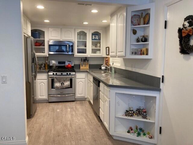 kitchen with white cabinetry, sink, stainless steel appliances, and light hardwood / wood-style floors