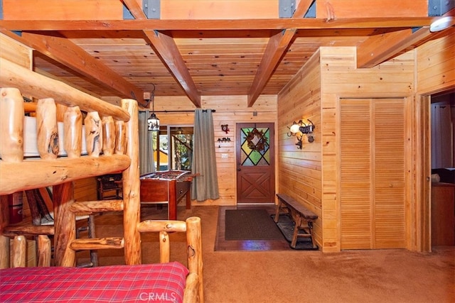 carpeted bedroom with beam ceiling, wooden walls, and wooden ceiling