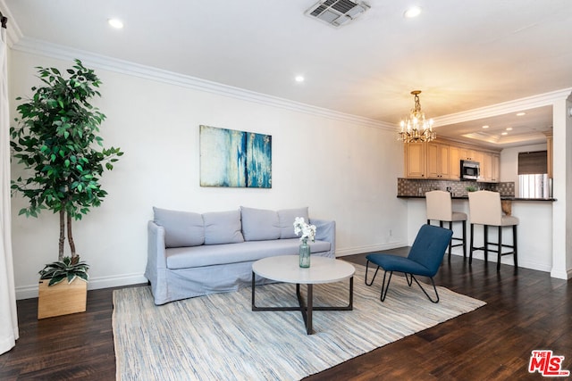 living room featuring dark hardwood / wood-style floors, an inviting chandelier, and ornamental molding