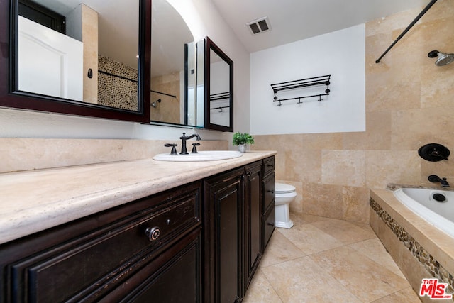 full bathroom featuring tiled shower / bath combo, tile patterned flooring, vanity, tile walls, and toilet