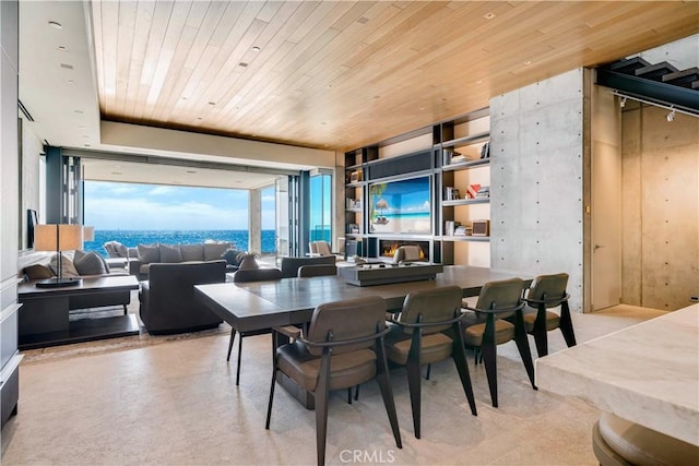 dining area with a water view, expansive windows, and wooden ceiling