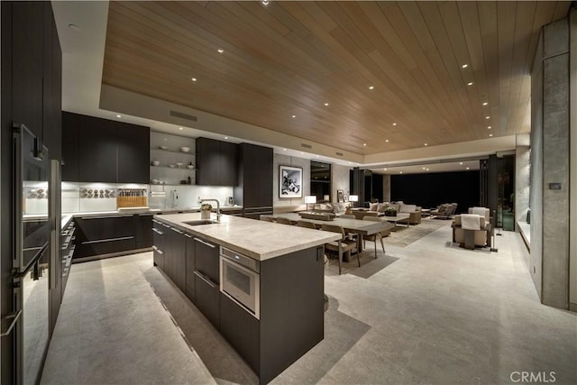 kitchen featuring a raised ceiling, a spacious island, wood ceiling, and sink