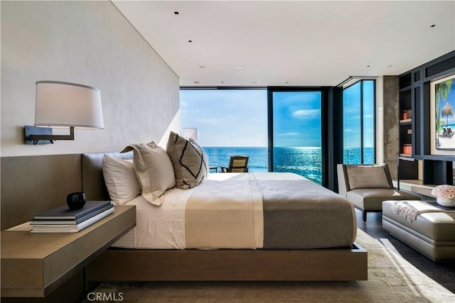 bedroom featuring hardwood / wood-style floors, expansive windows, and a water view