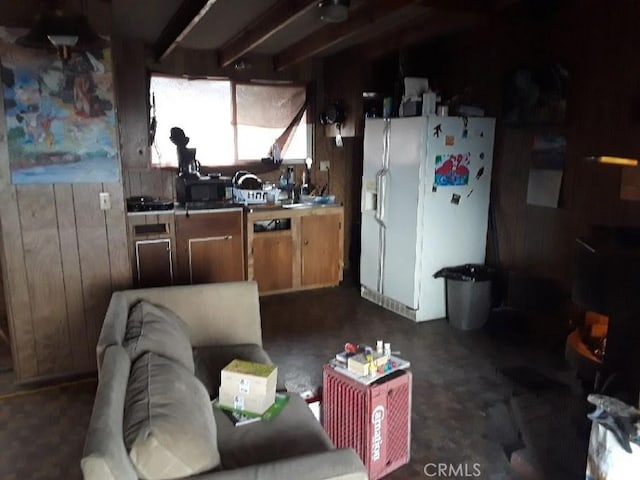 kitchen featuring tile countertops, wood walls, and white fridge with ice dispenser