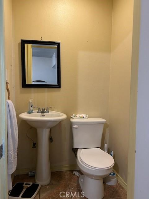 1227 Rolland Curtis Pl Unit 1227-1/2, Los Angeles, CA 90037 - half bath featuring toilet, baseboards, a sink, and tile patterned flooring