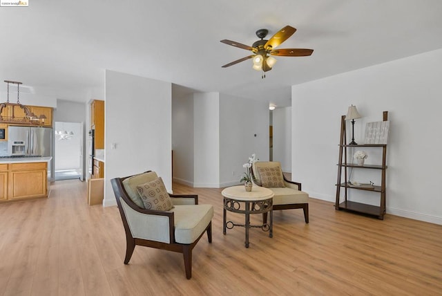 sitting room featuring light wood-type flooring and ceiling fan with notable chandelier