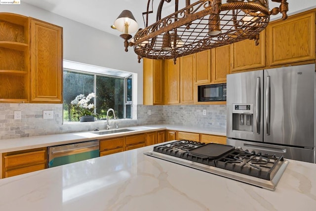 kitchen with appliances with stainless steel finishes, sink, light stone counters, and backsplash