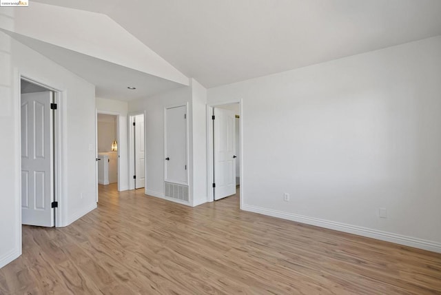 spare room with lofted ceiling and light hardwood / wood-style flooring