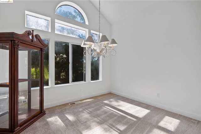 unfurnished dining area with high vaulted ceiling, carpet, and a chandelier