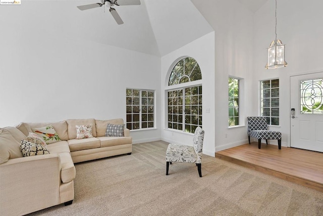 living room with high vaulted ceiling, ceiling fan with notable chandelier, and light wood-type flooring