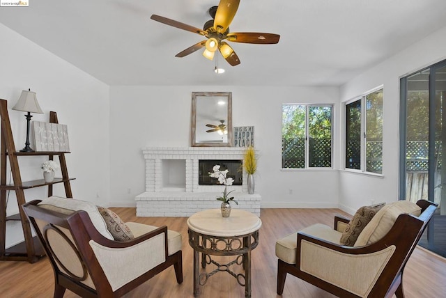 living area featuring ceiling fan, light hardwood / wood-style flooring, and a fireplace