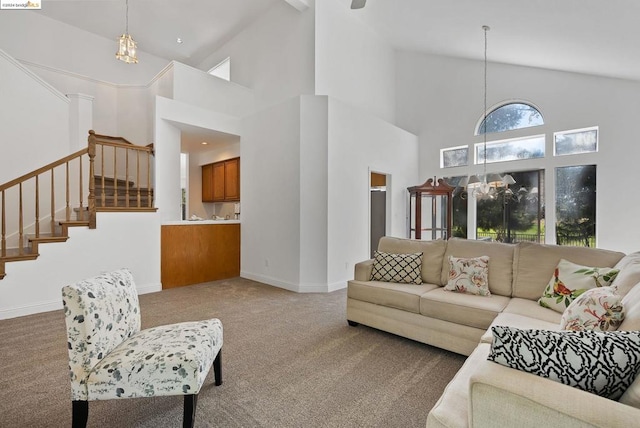 carpeted living room with a notable chandelier and high vaulted ceiling