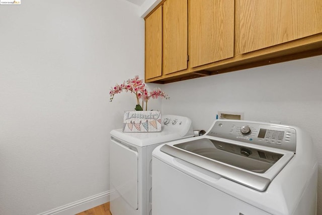 laundry room with independent washer and dryer, cabinets, and light wood-type flooring