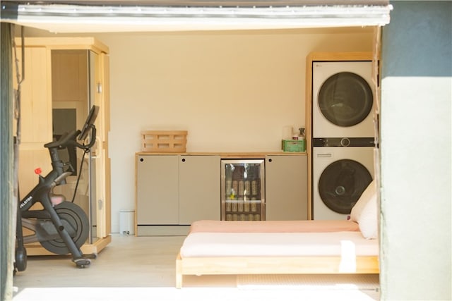 laundry area with light hardwood / wood-style floors, wine cooler, and stacked washer and clothes dryer